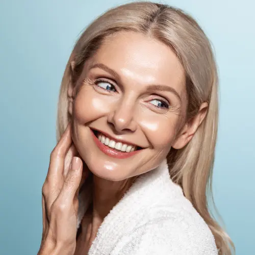 Beautiful 50s mid aged mature woman looking away isolated on blue. Mature old lady close up portrait. Healthy face skin care, middle age skincare cosmetics, cosmetology concept