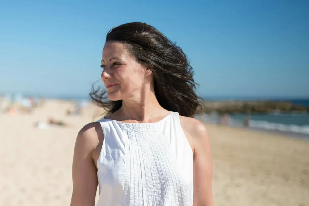 older woman in white on beach