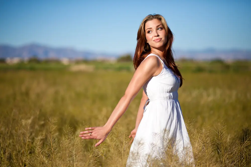 Girl in a white dress walking through wheat field.